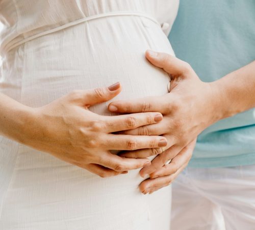 pexels-photo-4513731-4513731 Close-up of hands gently embracing a baby bump in a warm, serene setting.